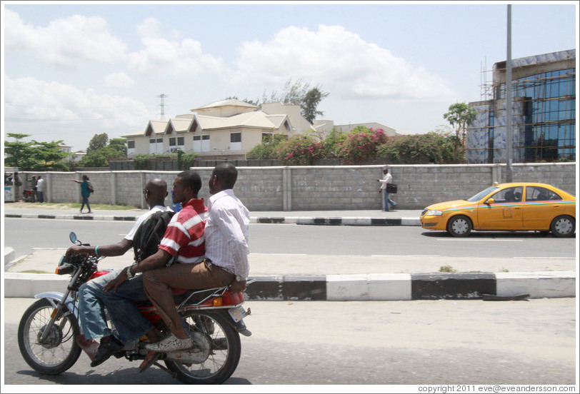 Three men on a motorcycle. Maroko Road, Victoria Island.