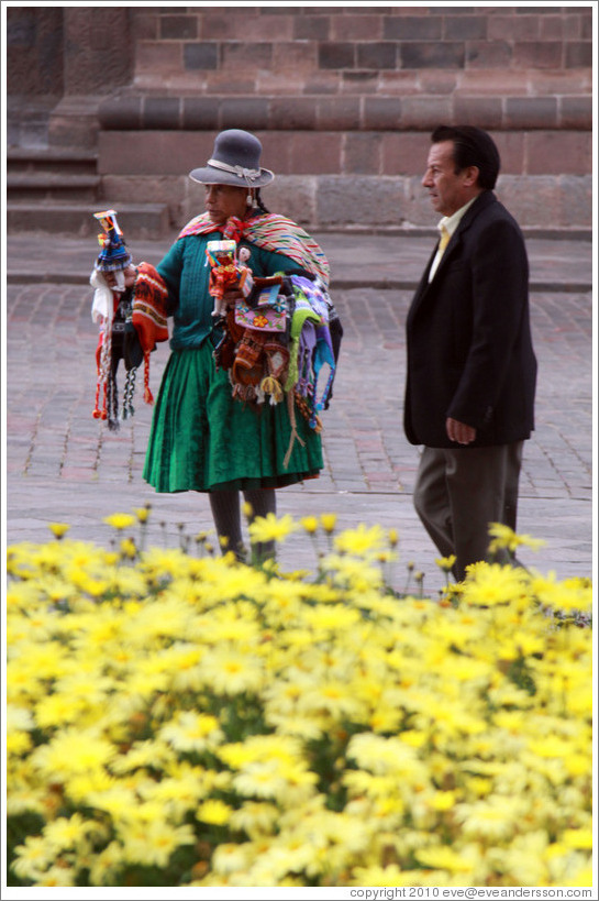 Female vendor in traditional wear and man in modern wear. Plaza de Armas.