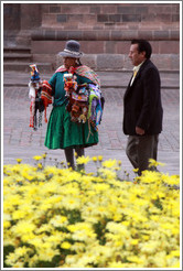 Female vendor in traditional wear and man in modern wear. Plaza de Armas.