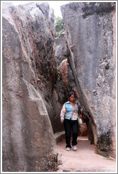 Woman walking between tall rocks, Qenko ruins.