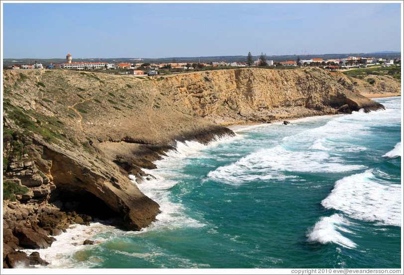 Cliff with a sea cave, with the town of Sagres behind.