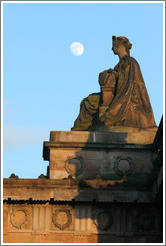 The moon appearing to hover near a statue of a woman atop the Royal Scottish Academy&#8206; building.