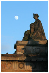 The moon appearing to hover near a statue of a woman atop the Royal Scottish Academy&#8206; building.