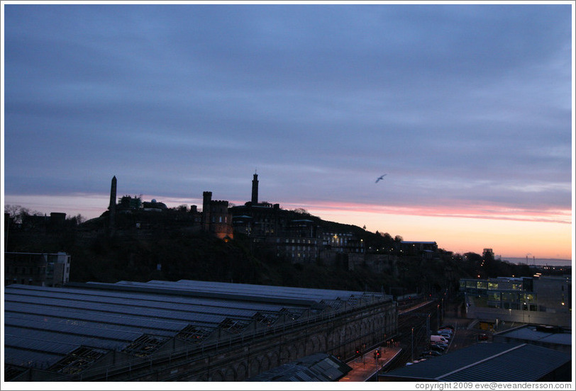 Edinburgh Waverley railway station's roof, with Calton Hill in the background, at sunrise.