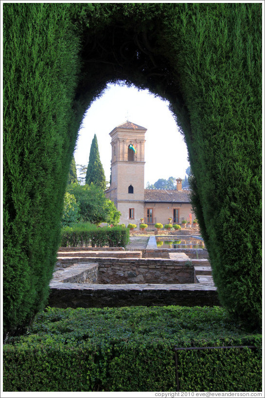 Parador de San Francisco through a hole in the hedge, Alhambra.