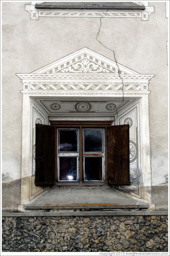 Window, with typical Romansh adornment, and a crack running through the wall.  