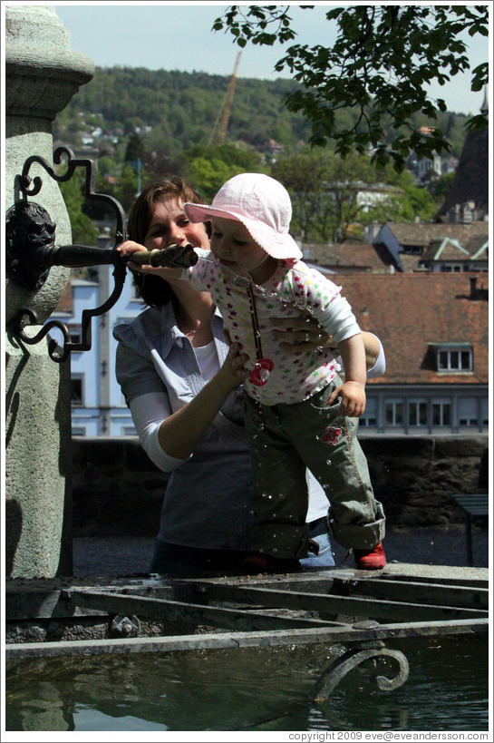 Baby drinking from fountain.  Clean, mountain water comes out of fountains in Z?rich.  Lindenhof.  Altstadt (Old Town).