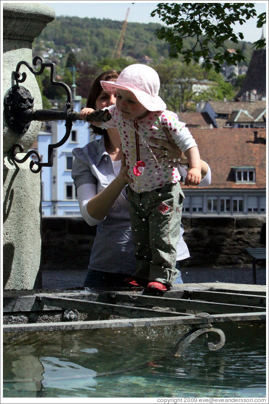 Baby drinking from fountain.  Clean, mountain water comes out of fountains in Z?rich.  Lindenhof.  Altstadt (Old Town).