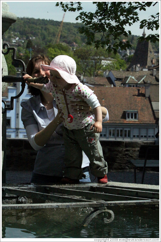 Baby drinking from fountain.  Clean, mountain water comes out of fountains in Z?rich.  Lindenhof.  Altstadt (Old Town).