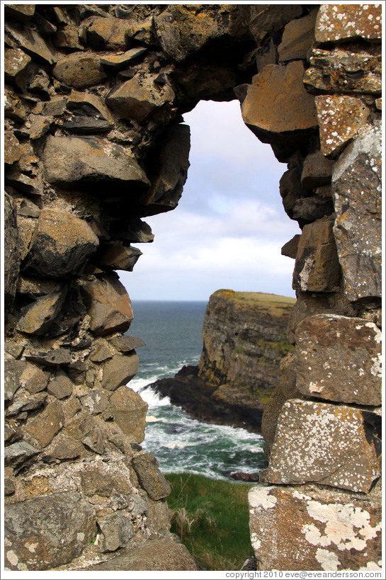 View of a sea cliff through a hole in the wall of Dunluce Castle.