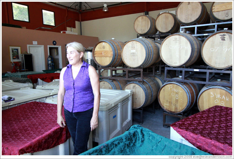 Winemaker Katy Lovell of Poetic Cellars standing among containers of fermenting grapes under blankets.