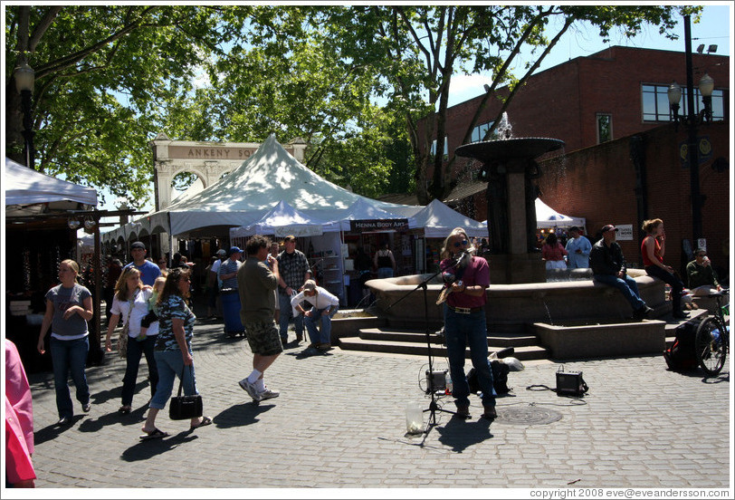 Street performer with one arm and two instruments.  Saturday Market.