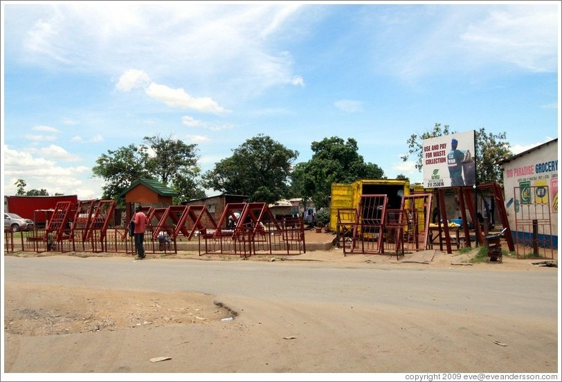 Construction materials for sale on the roadside.  Billboard reads: "Use and pay for waste collection."